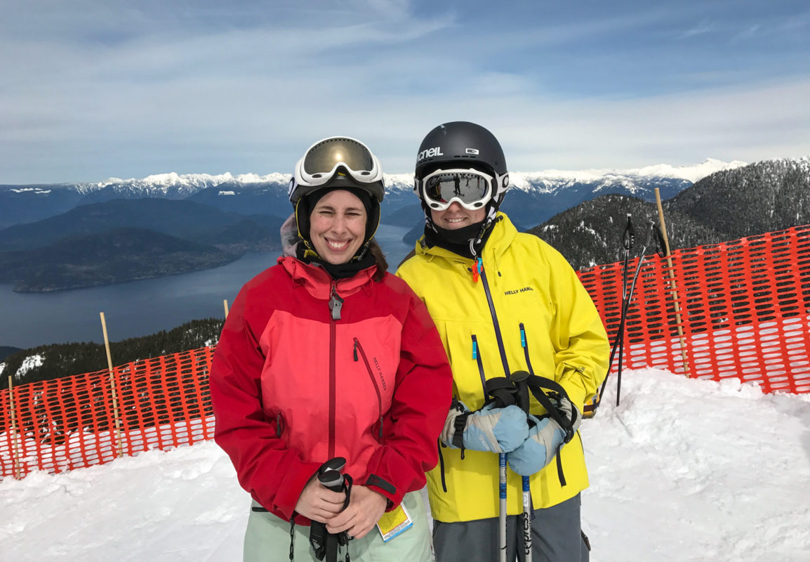 Katie and Emily Teed skiing at Cypress Mountain, overlooking Howe Sound in the background.